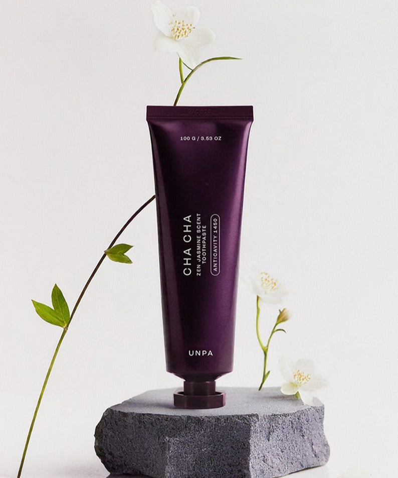 UNPA Cha CHa Zen Jasmine Scent 1450 High Fluoride Toothpaste 100g UNPA, tube violet sur pierre, fleurs de jasmin blanches.