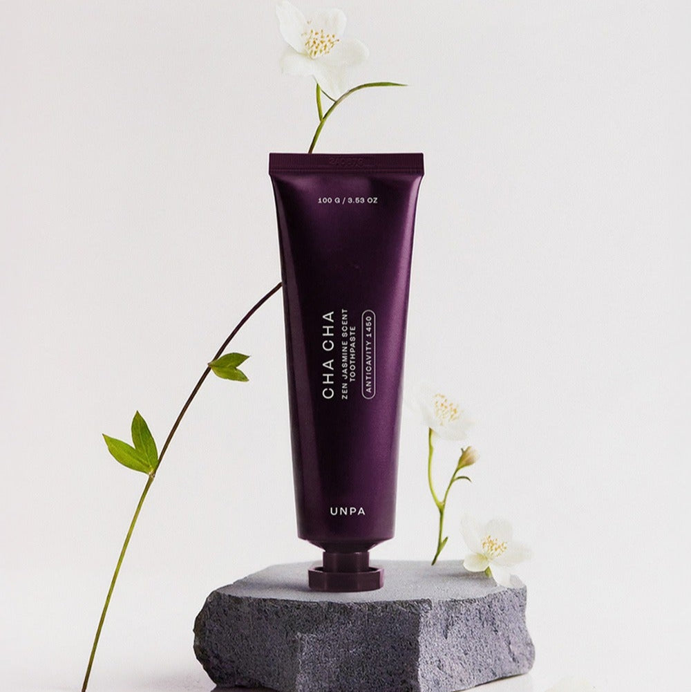 UNPA Cha CHa Zen Jasmine Scent 1450 High Fluoride Toothpaste 100g UNPA, tube violet sur pierre, fleurs de jasmin blanches.