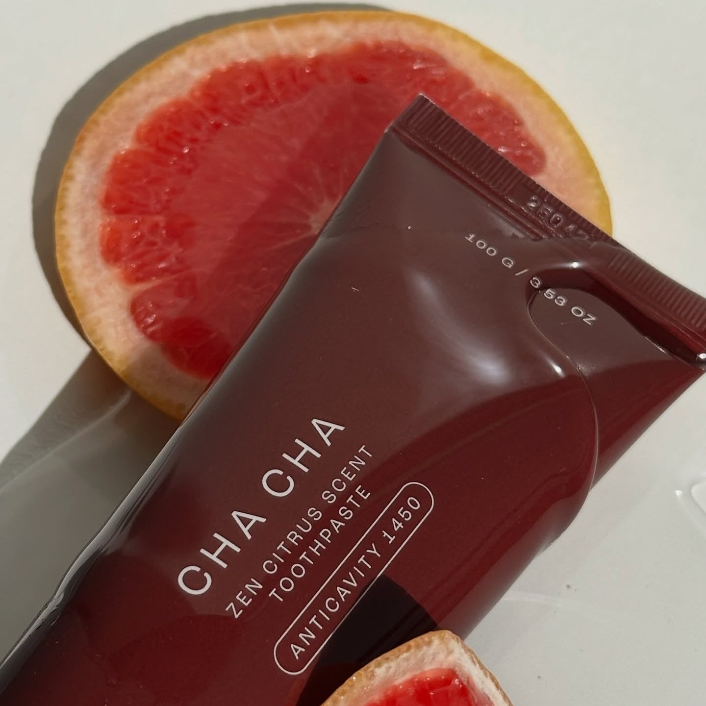 UNPA Cha Cha Zen Grapfruit Scent 1450 High Fluoride Toothpaste 100g de la marque UNPA, boîte sur tranche de pamplemousse