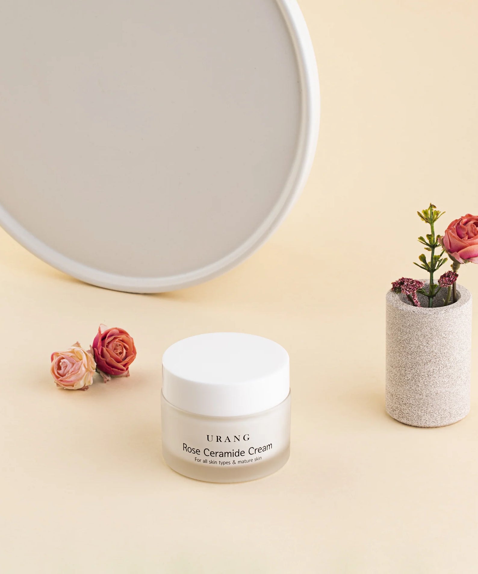 Crème URANG Rose Ceramide 50ml sur fond beige avec roses décoratives à côté, hydratation intense et protection pour la peau.