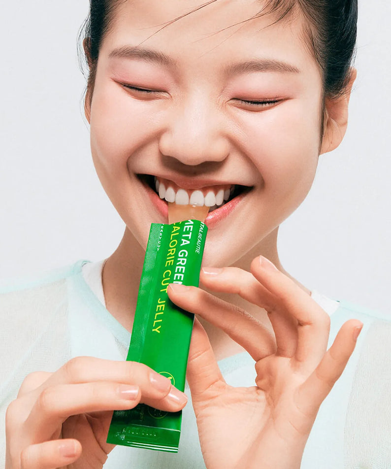 Jeune femme souriante consommant un sachet de VITALBEAUTIE Meta Green Calorie Cut Jelly 10 Packets, un complément actif pour la gestion du poids.