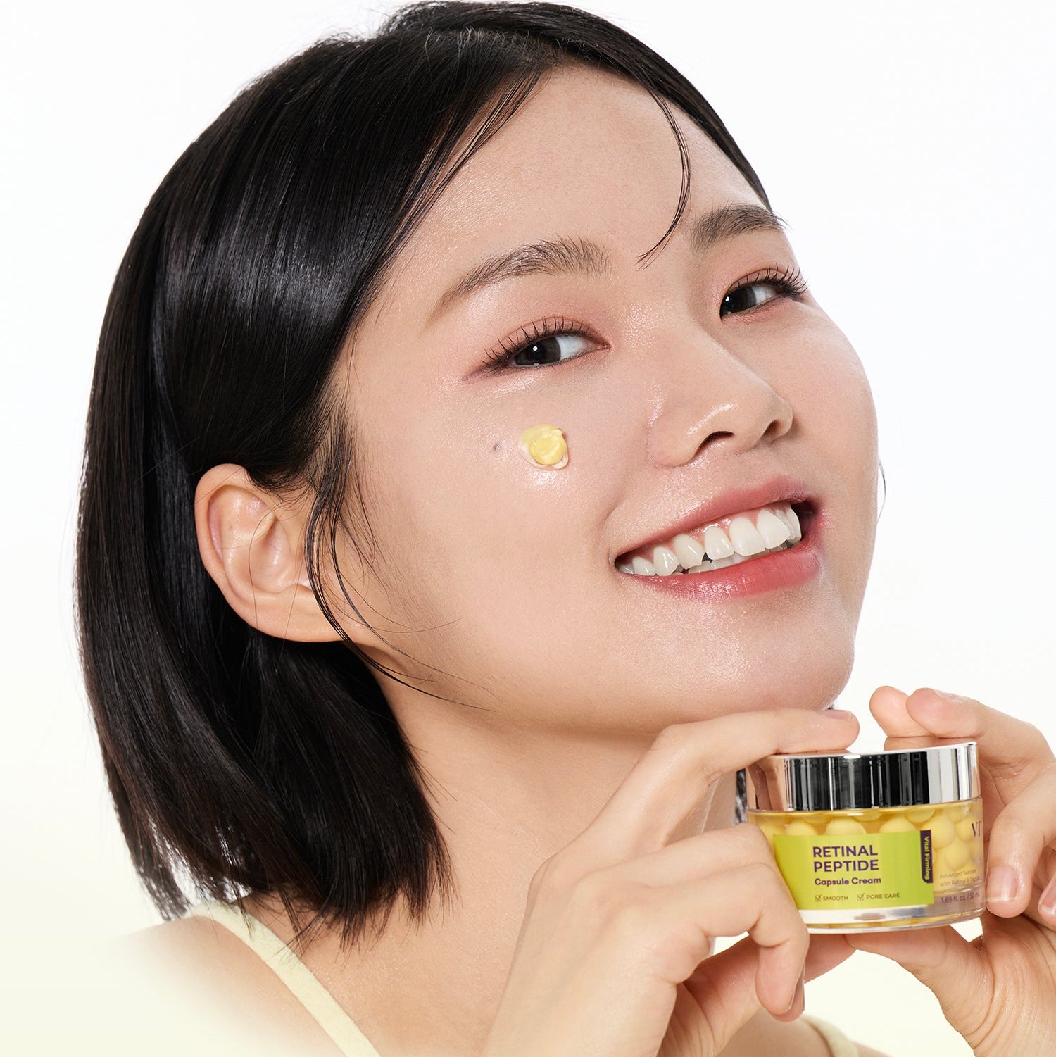 VT COSMETIC Retinal Peptide Capsule Cream 50ml, pot cosmétique de la marque, femme souriante en studio sur fond clair.