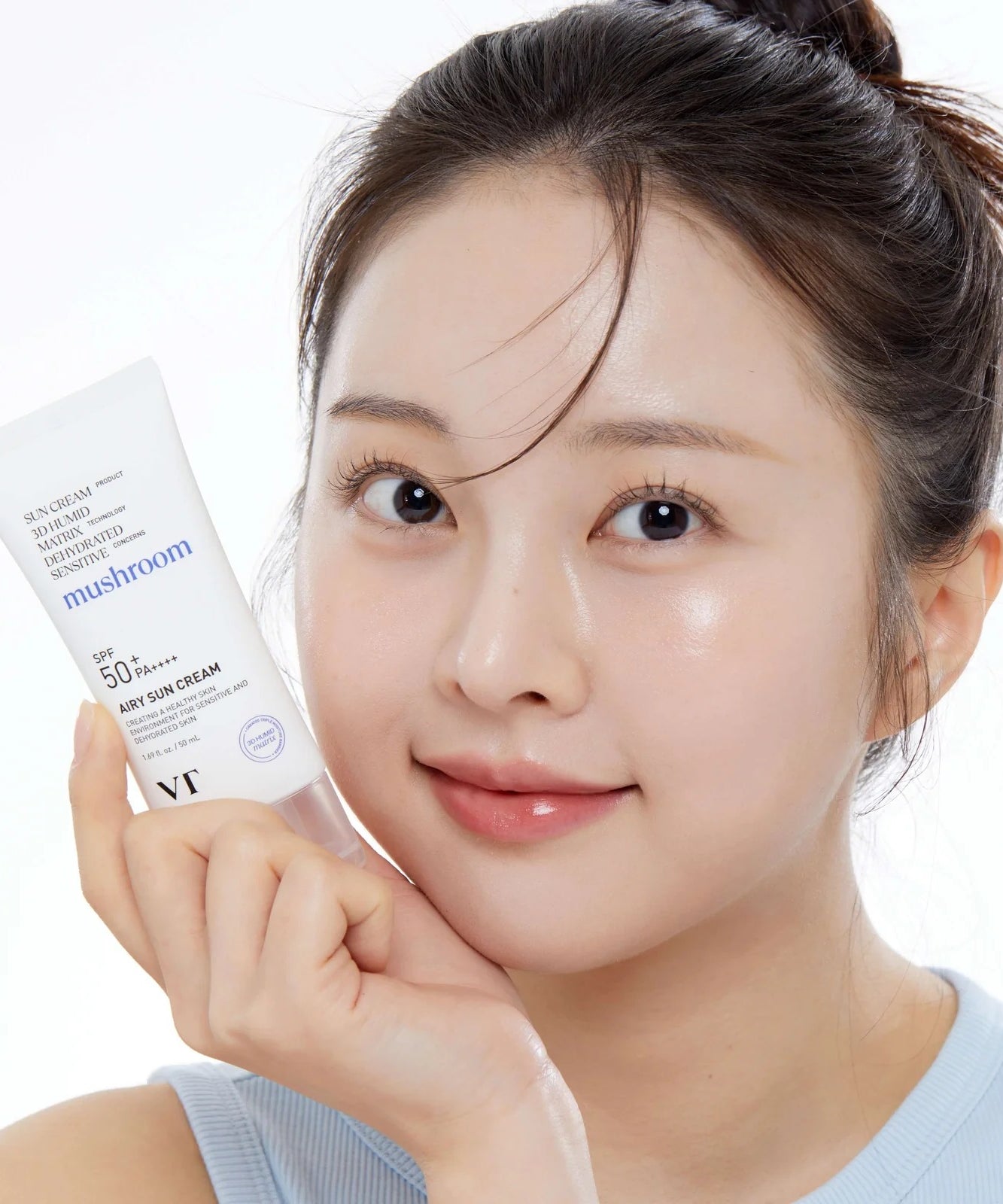 VT COSMETICS Airy Sunscreen 50ml, femme tenant le tube, peau lumineuse, contexte soins solaires, marque VT Cosmetics.