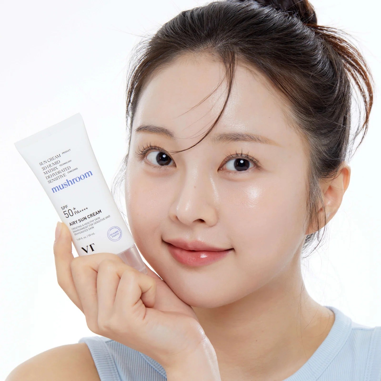 VT COSMETICS Airy Sunscreen 50ml, femme tenant le tube, peau lumineuse, contexte soins solaires, marque VT Cosmetics.
