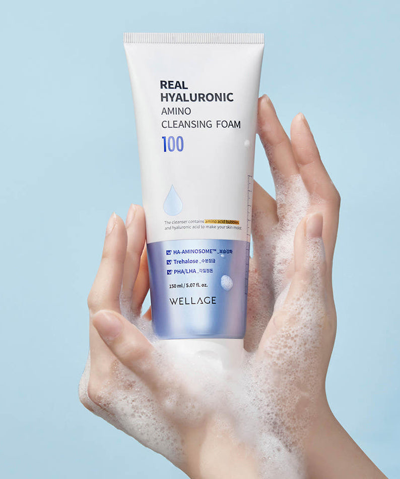 WELLAGE  Real Hyaluronic Amino Cleansing Foam 150ml : tube sur fond bleu, mains avec mousse, soin nettoyant.