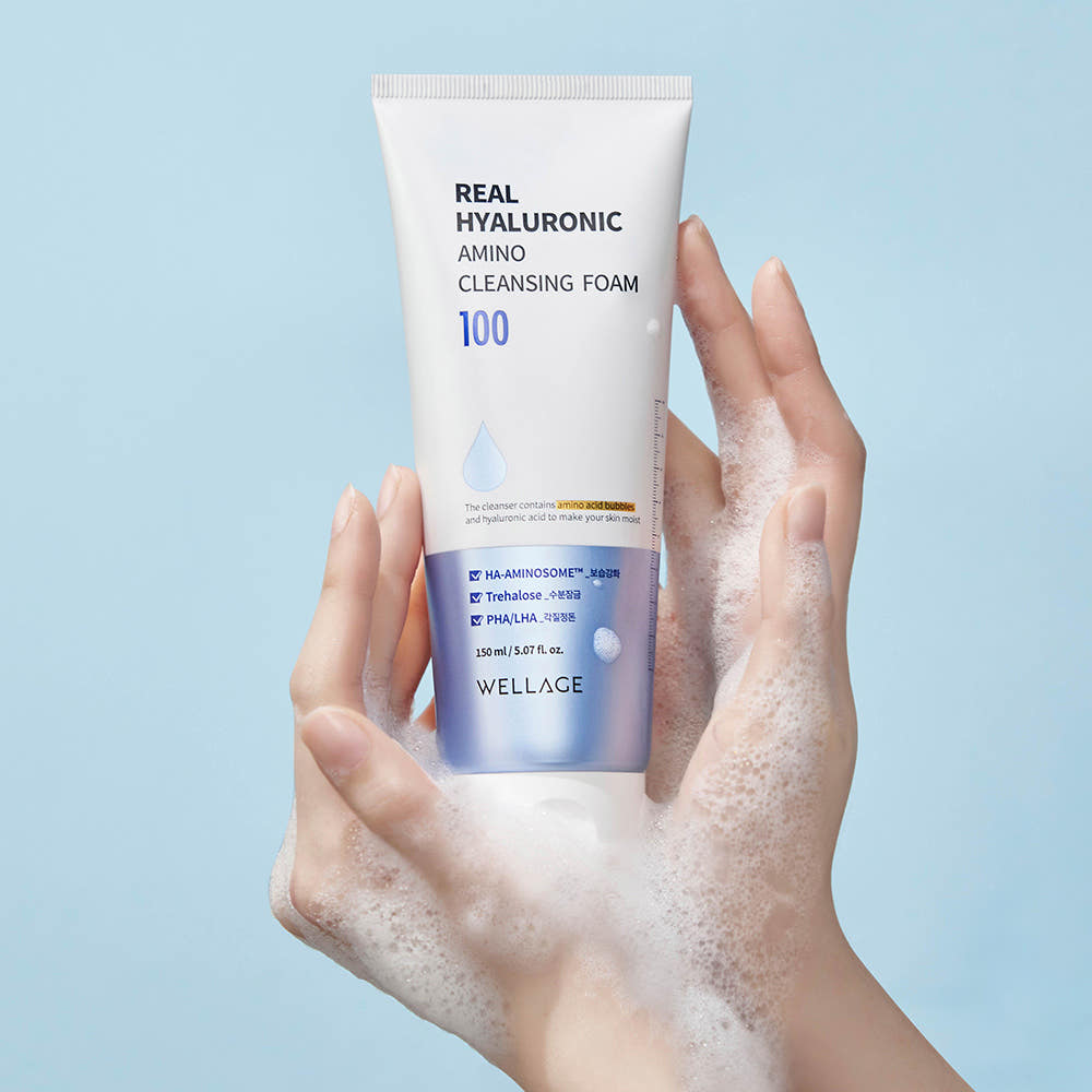 WELLAGE  Real Hyaluronic Amino Cleansing Foam 150ml : tube sur fond bleu, mains avec mousse, soin nettoyant.