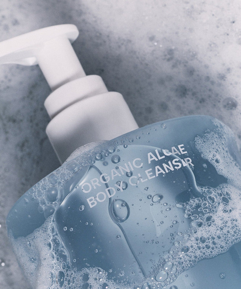 WHAMISA Organic Algae Fermented Body Cleanser 490ml, bouteille WHAMISA dans un bain moussant bleu, contexte visuel produit.