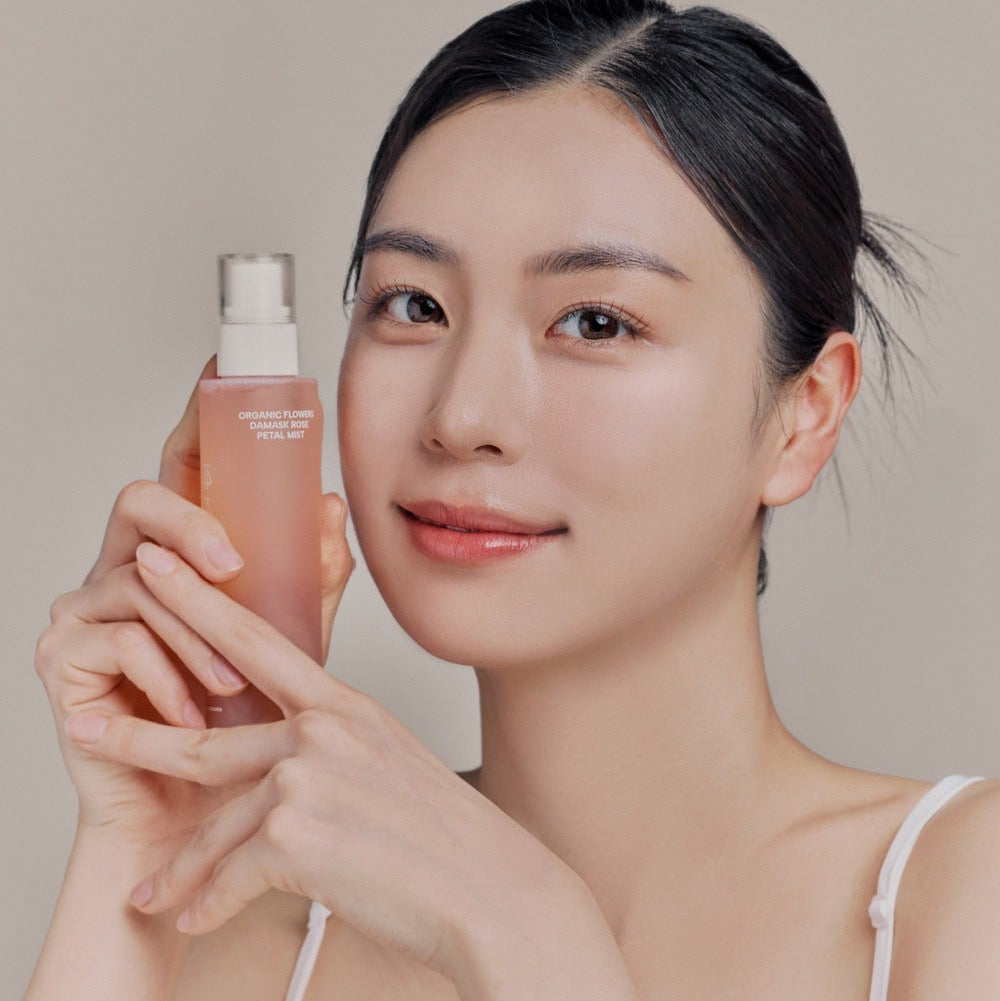 WHAMISA Organic Flower Fermented Rose Petal Mist 100ml, femme tenant le spray visage au fond clair, ambiance beauté.