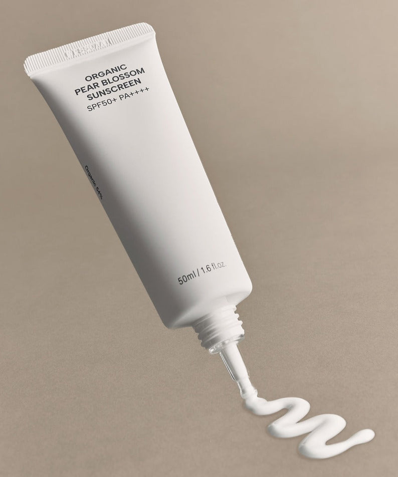 WHAMISA Organic Pear Blossom Fermented Sunscreen 50ml, tube blanc sur fond beige, crème solaire bio en contexte beauté
