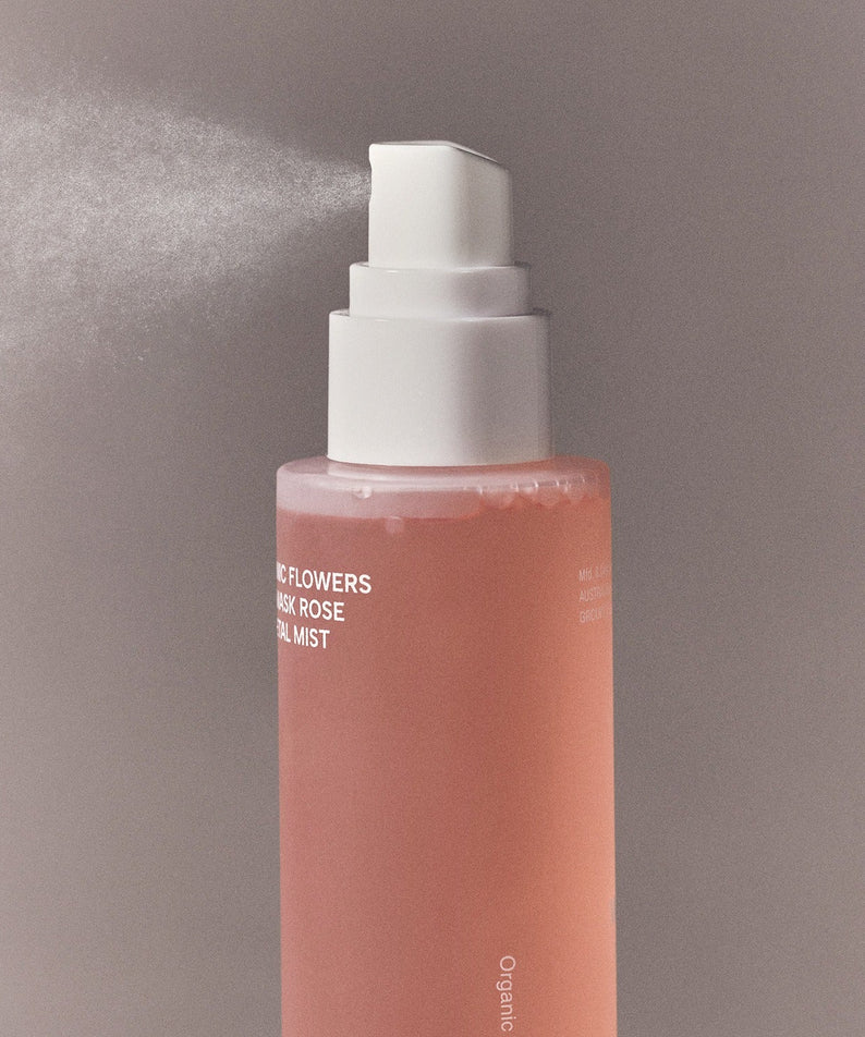 Vaporisateur WHAMISA Organic Flower Fermented Rose Petal Mist 100ml diffusant une brume fine sur fond gris élégant.