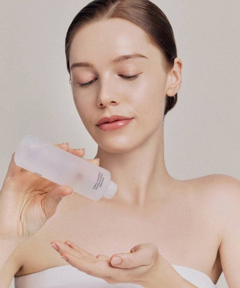 Femme appliquant le WHAMISA Organic Pear Blossom Fermented Essence Toner 160ml sur sa main pour des soins de la peau bio.