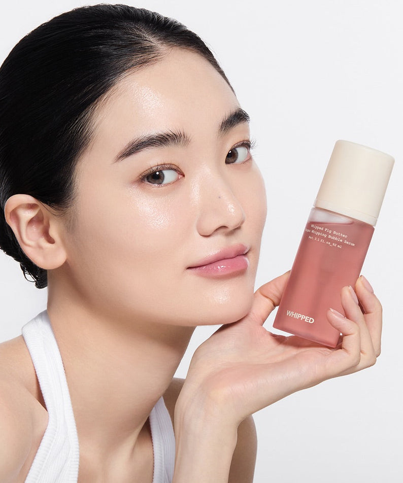 WHIPPED Butter Vegan Whipping Bubble Serum 92ml sur peau éclatante, femme en studio tenant le flacon rose.