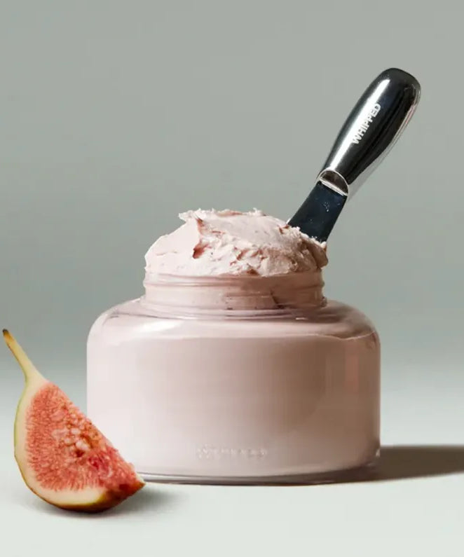 WHIPPED Vegan Topping Body Butter 190g, pot crème fouettée vegan sur fond clair, spatule et figue, ambiance beauté.