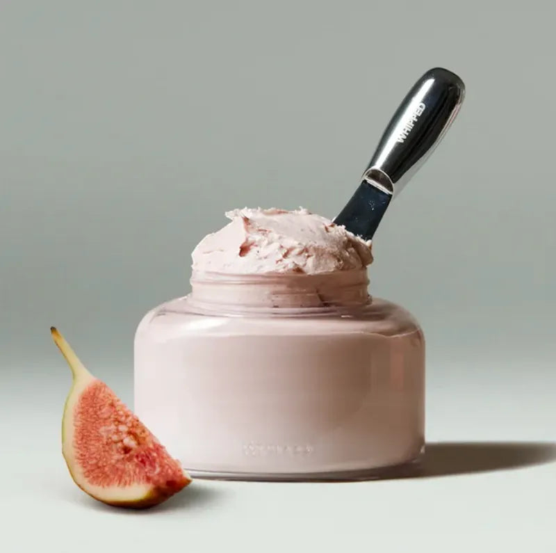 WHIPPED Vegan Topping Body Butter 190g, pot crème fouettée vegan sur fond clair, spatule et figue, ambiance beauté.