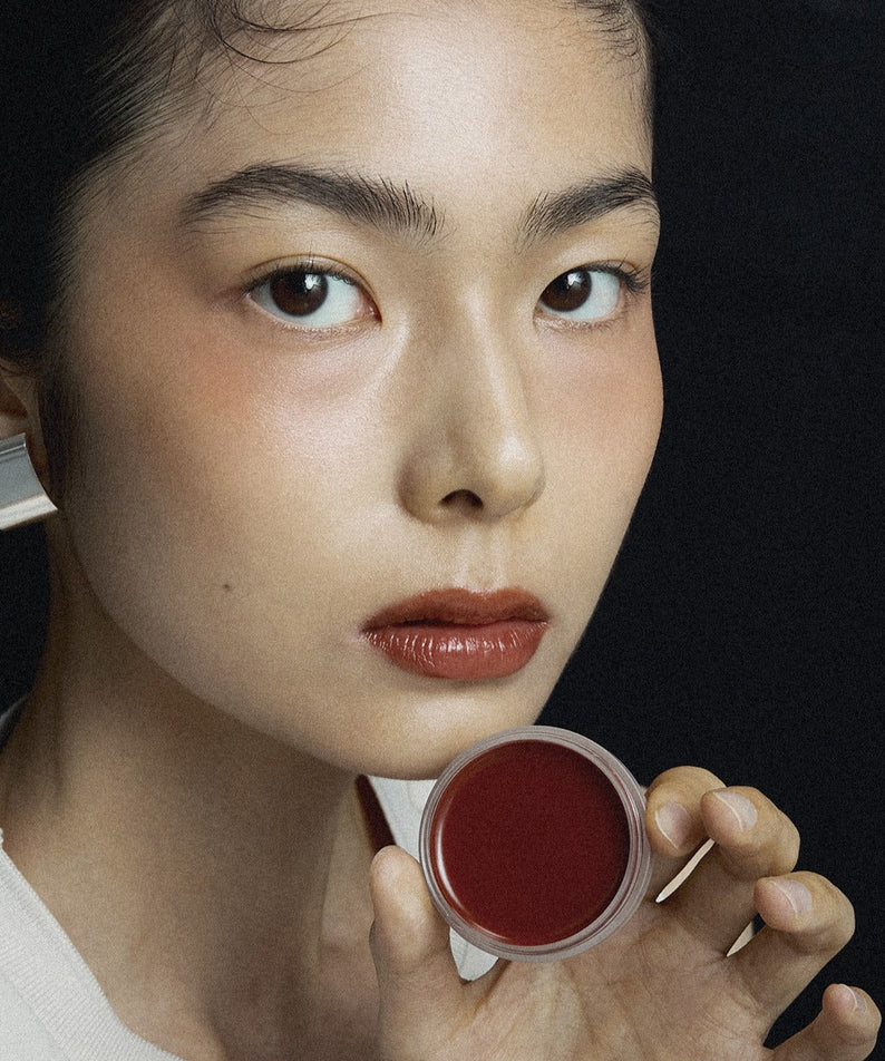 XOUL Ever Moist Volume Lip Balm 8g, femme tenant le baume sur fond sombre, lèvres hydratées, marque XOUL visible.