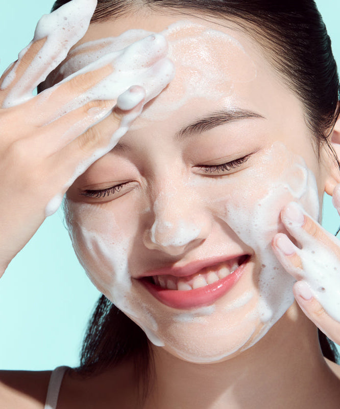 Femme utilisant ANUA PDRN Hyaluronic Acid Moisture Cleansing Foam 150ml avec des bulles moussantes sur le visage.