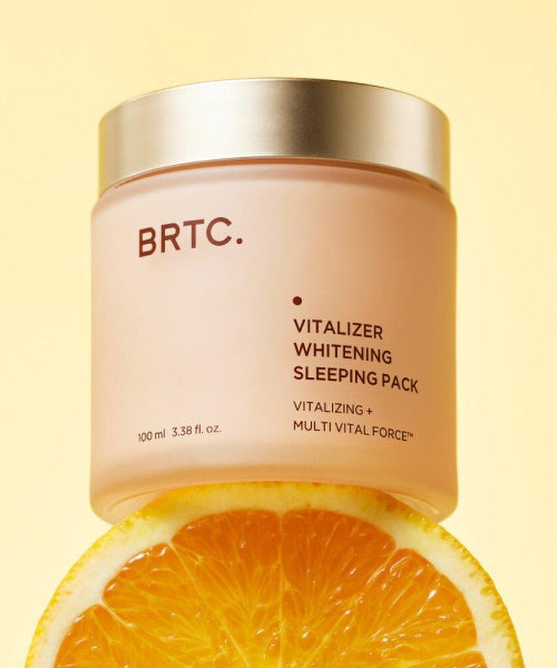 BRTC Vitalizer Whitening Sleeping Pack 100ml de BRTC, pot crème sur fond jaune, avec rondelle d’orange en contexte visuel.