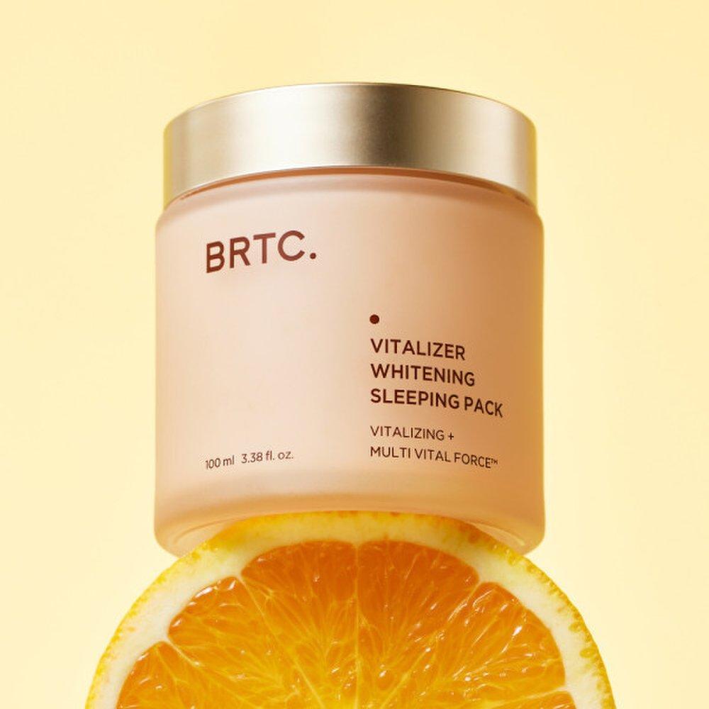 BRTC Vitalizer Whitening Sleeping Pack 100ml de BRTC, pot crème sur fond jaune, avec rondelle d’orange en contexte visuel.