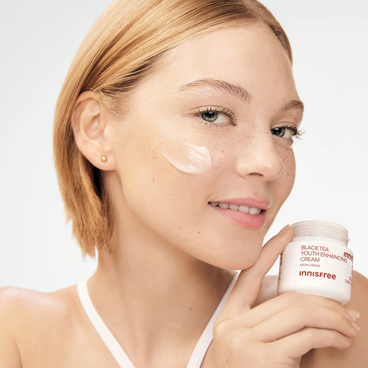 INNISFREE Black Tea Youth Enhancing Cream 50ml : pot en main, peau hydratée, fond clair, visage féminin, mise en scène beauté.